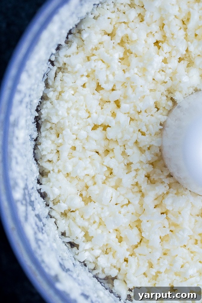 Crafting Delicious Cauliflower Rice 5 Close-up shot of perfectly riced cauliflower in a food processor, showcasing its granular texture