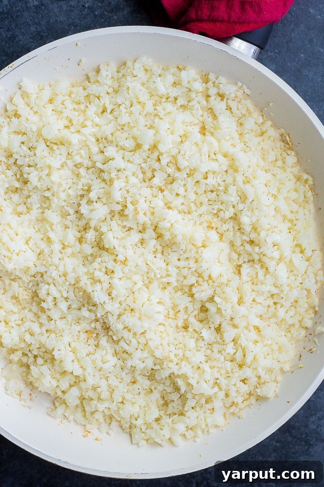 Crafting Delicious Cauliflower Rice 6 Large pan filled with perfectly cooked and seasoned cauliflower rice, ready for serving