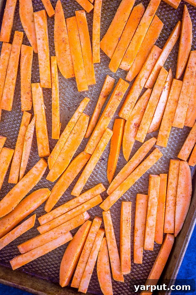 Golden Crispy Baked Sweet Potato Fries 4 Uncooked sweet potato fries, uniformly sliced, spread out on a baking tray, lightly seasoned and ready for the oven