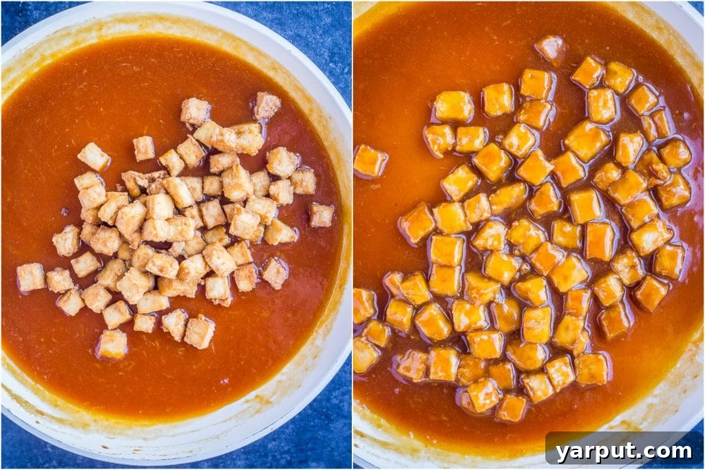 Zesty Vegan Orange Tofu 4 Tofu pieces being mixed into the vibrant orange sauce in a skillet, creating the vegan orange tofu dish