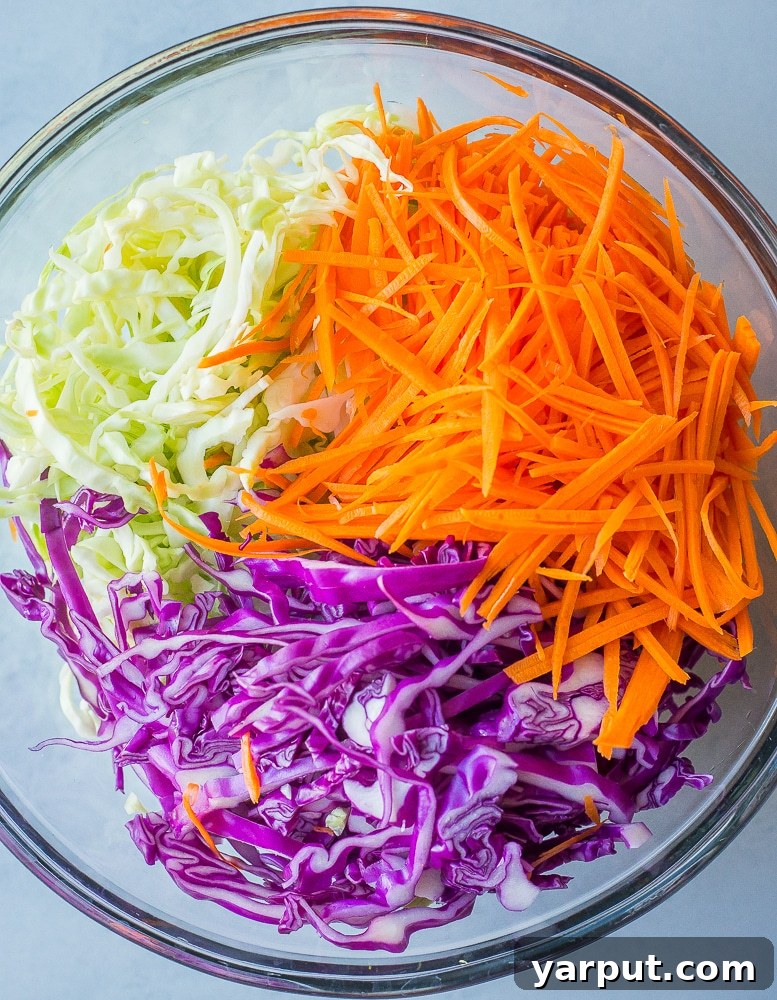 Quick Vegan Coleslaw No Refined Sugar 3 Freshly shredded green cabbage and carrots in a large mixing bowl, prepared for making homemade coleslaw.
