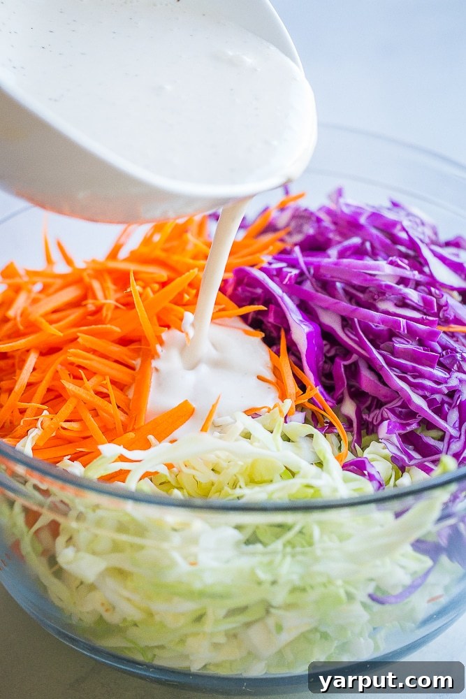 Quick Vegan Coleslaw No Refined Sugar 5 A close-up shot of creamy homemade coleslaw dressing being generously poured over a bowl of fresh shredded vegetables.
