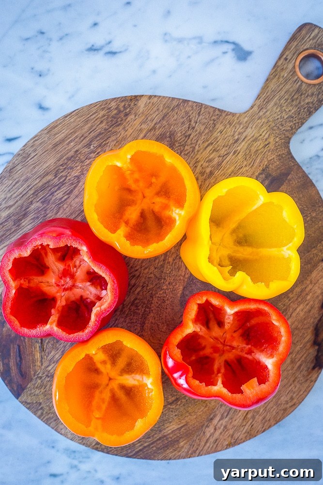 Wholesome Cauliflower Rice Stuffed Peppers 3 Brightly colored bell peppers, halved and prepared for stuffing, laid out on a cutting board.