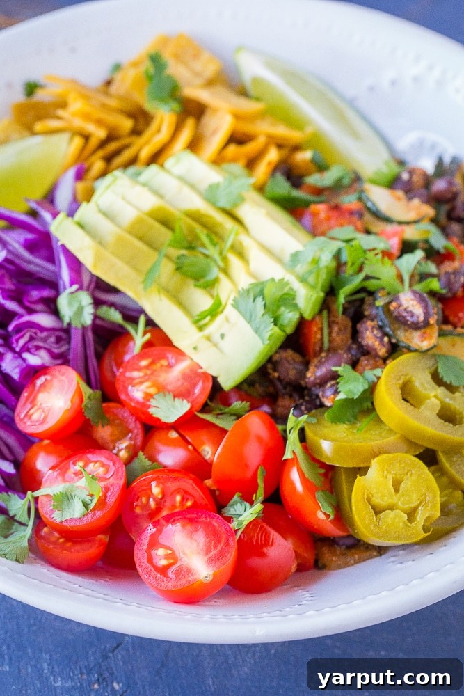 Vibrant Vegan Taco Power Bowls 6 Another close-up shot of a single vegan taco bowl, emphasizing the appealing blend of textures from crispy tortillas, creamy avocado, and seasoned beans.
