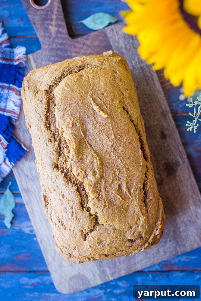 Simple One-Bowl Naturally Sweetened Pumpkin Bread 4 A whole loaf of Healthy Pumpkin Bread on a rustic wooden cutting board, ready to be sliced and served.