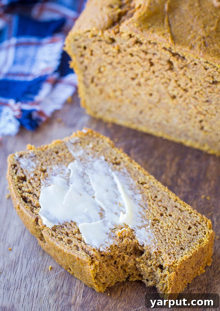 Simple One-Bowl Naturally Sweetened Pumpkin Bread 6 A slice of Healthy Pumpkin Bread topped with a pat of melted butter, inviting to be eaten.