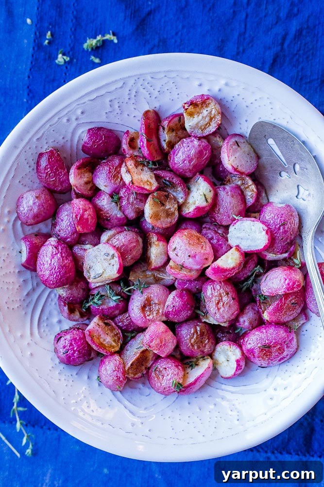 Oven-Roasted Radishes with Garlic and Fresh Herbs 4 A close-up shot of perfectly roasted radishes, golden and tender, in a white bowl set on a rustic blue napkin, garnished with fresh thyme.