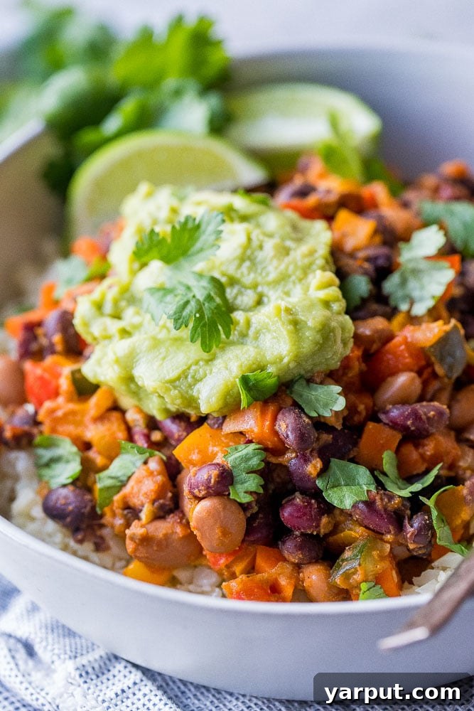 Hearty Vegetable Chili 4 A close-up shot of rich chili beans and vegetables in a bowl, topped with creamy guacamole and fresh cilantro, enticing and ready to serve.