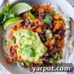 A vibrant bowl of vegan chili beans garnished with fresh guacamole and cilantro, ready to be enjoyed.