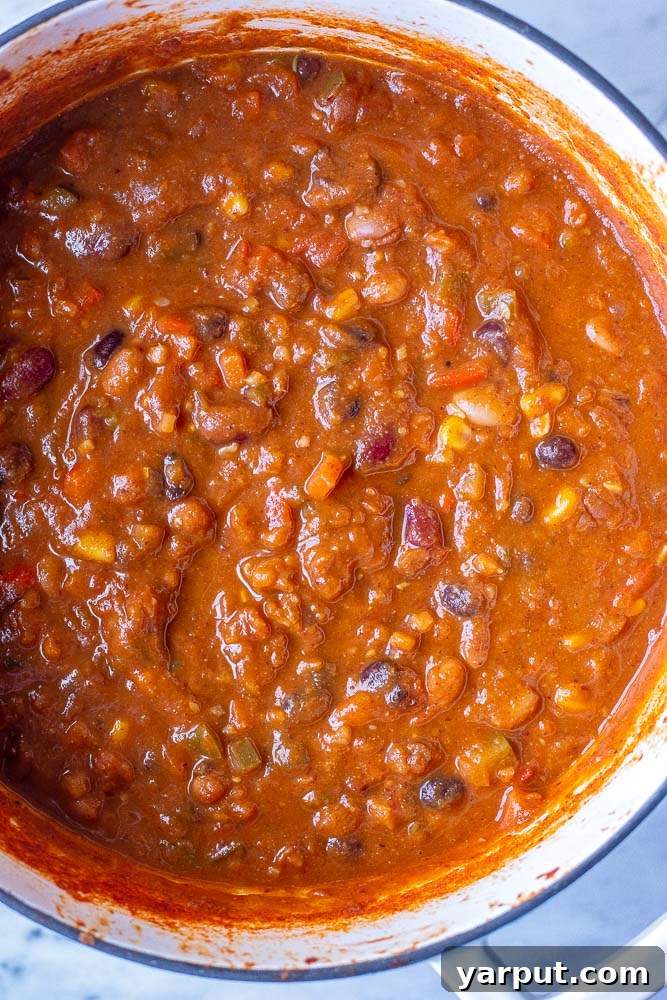 A large pot filled with rich, thick vegetarian chili simmering on the stovetop, showcasing its hearty texture and vibrant colors.
