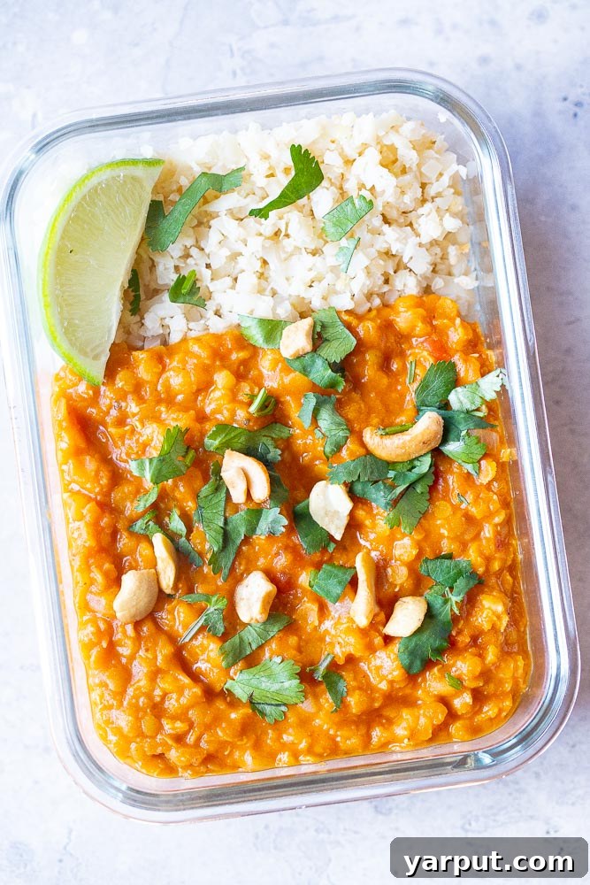 Simple Red Lentil Delight 5 Red lentil curry served in a meal prep container with cauliflower rice and fresh lime, ready to eat