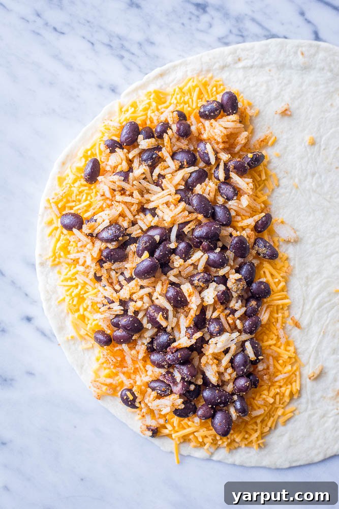 No-Fuss Rice and Bean Quesadillas 4 A close-up view of a tortilla being prepared, with shredded cheese and a hearty scoop of rice and bean filling on one half, ready for folding.