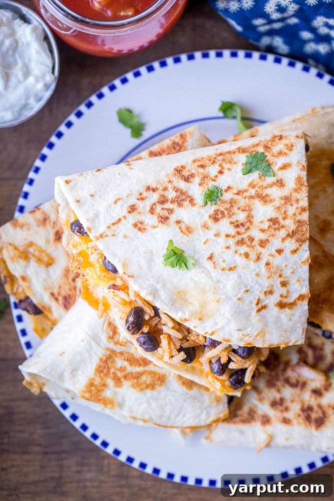 No-Fuss Rice and Bean Quesadillas 5 A vibrant plate of finished rice and bean quesadillas, cut into triangles and ready to be served, showcasing their golden crust and savory filling.