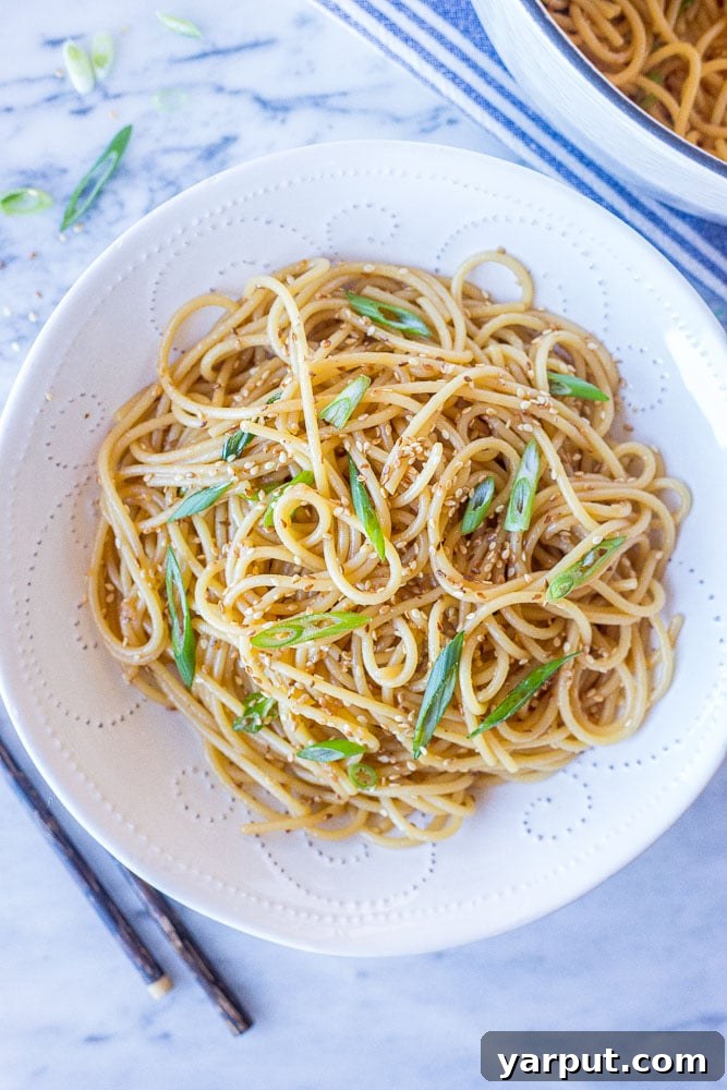 Big bowl of sesame noodles, garnished with sesame seeds and green onions