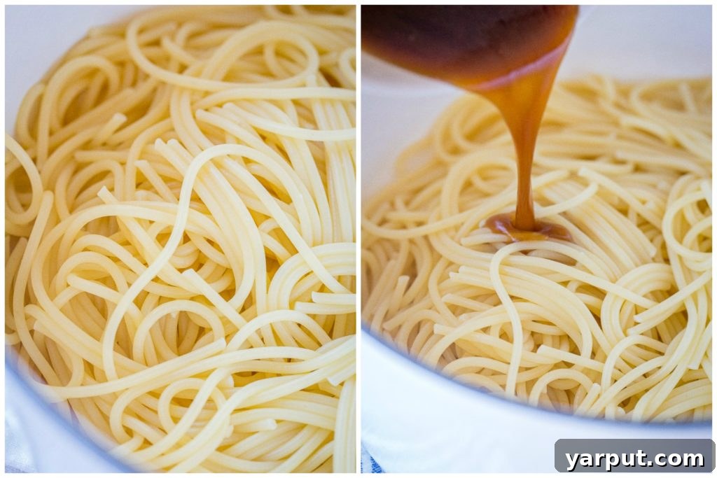 A hand pouring the sesame sauce over cooked noodles in a large pot