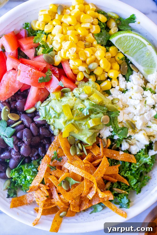 Vibrant Mexican Kale Salad with Cumin-Lime Vinaigrette 5 A vibrant and colorful close-up of the Mexican Kale Salad, showing a rich mix of ingredients including deep green massaged kale, bright yellow corn kernels, black beans, red diced tomatoes, creamy avocado slices, and crunchy pumpkin seeds, all artfully arranged and ready to be enjoyed.