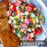 A vibrant bowl of Easy Chickpea Salad with fresh vegetables and pita bread