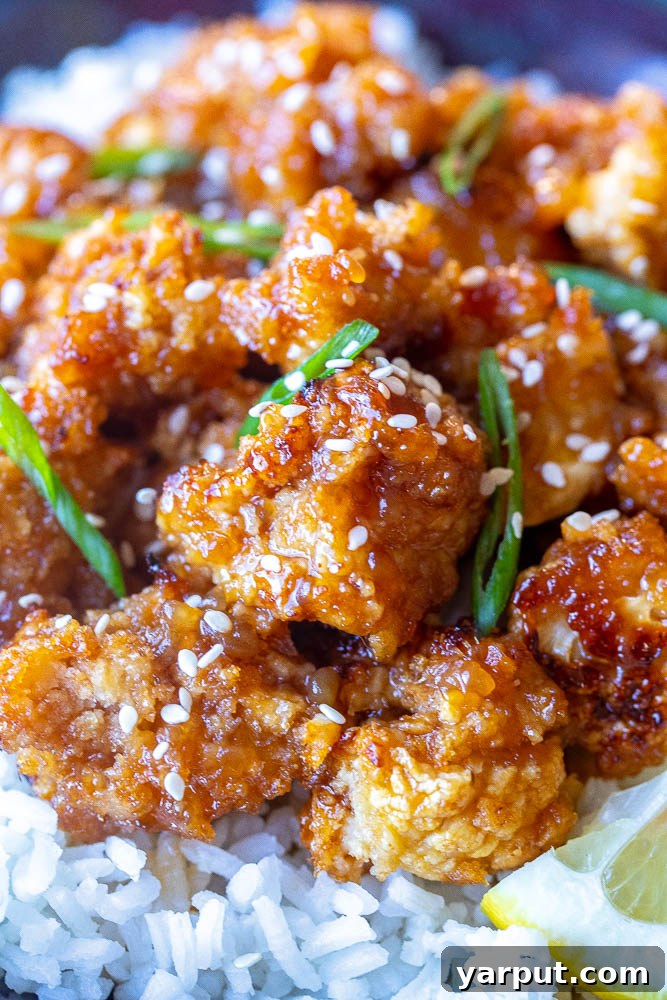 Lemon-Glazed Roasted Cauliflower 4 A close-up photograph showcasing a single piece of perfectly baked sticky lemon cauliflower, highlighting its crispy texture and the glistening homemade lemon sauce.