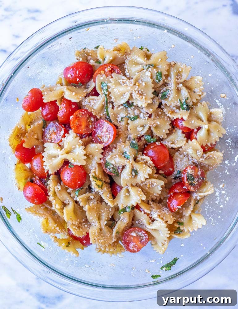 Vibrant Bruschetta Pasta Salad with Parmesan 4 Bruschetta pasta salad being mixed in a large bowl, showcasing its fresh ingredients