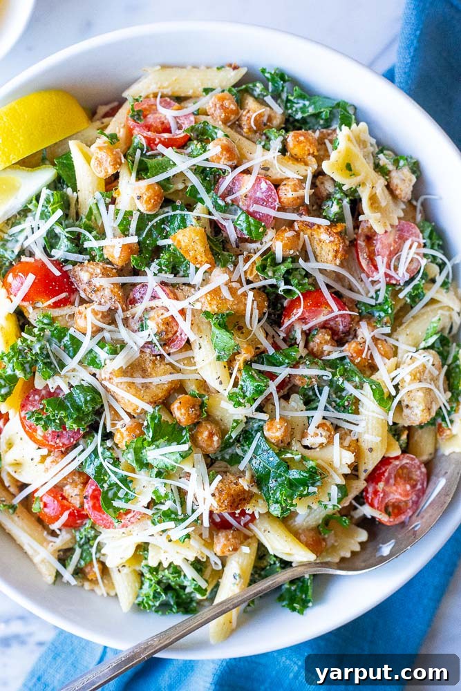 Elevated Kale Caesar Pasta 4 A close-up view of a vibrant bowl of Kale Caesar Pasta Salad, showcasing the crispy chickpeas, halved cherry tomatoes, and perfectly coated pasta
