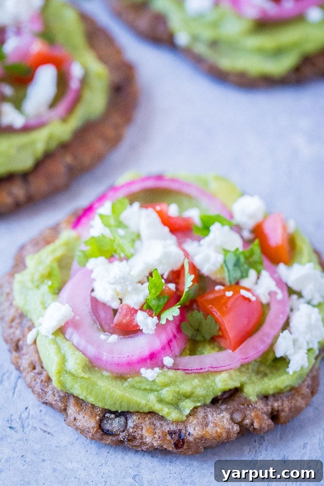 Vibrant Guacamole Tostadas with Black Bean Crisps 4 A beautifully arranged guacamole tostada, showcasing its vibrant layers of guacamole, fresh vegetables, and cheese.