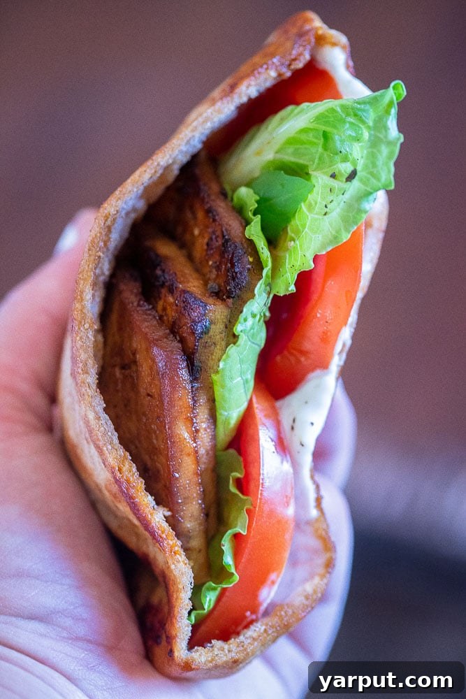 Plant-Based BLT Pockets 5 A hand holding a vegan BLT pita, showcasing its delicious fillings