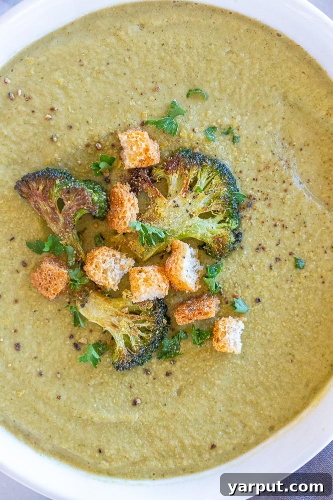 A close-up view of a steaming bowl of easy roasted broccoli soup, highlighting its rich color and smooth texture.