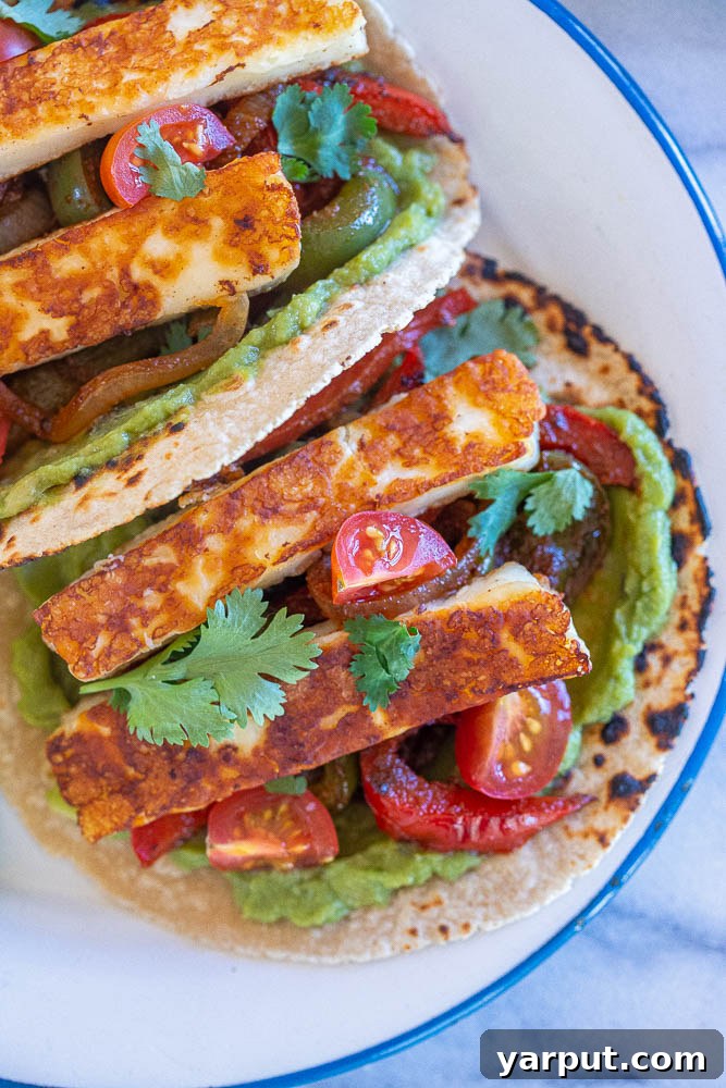 Sizzling Halloumi Fajitas 6 close up to vegetarian fajitas on a plate, showcasing the assembly with fresh toppings