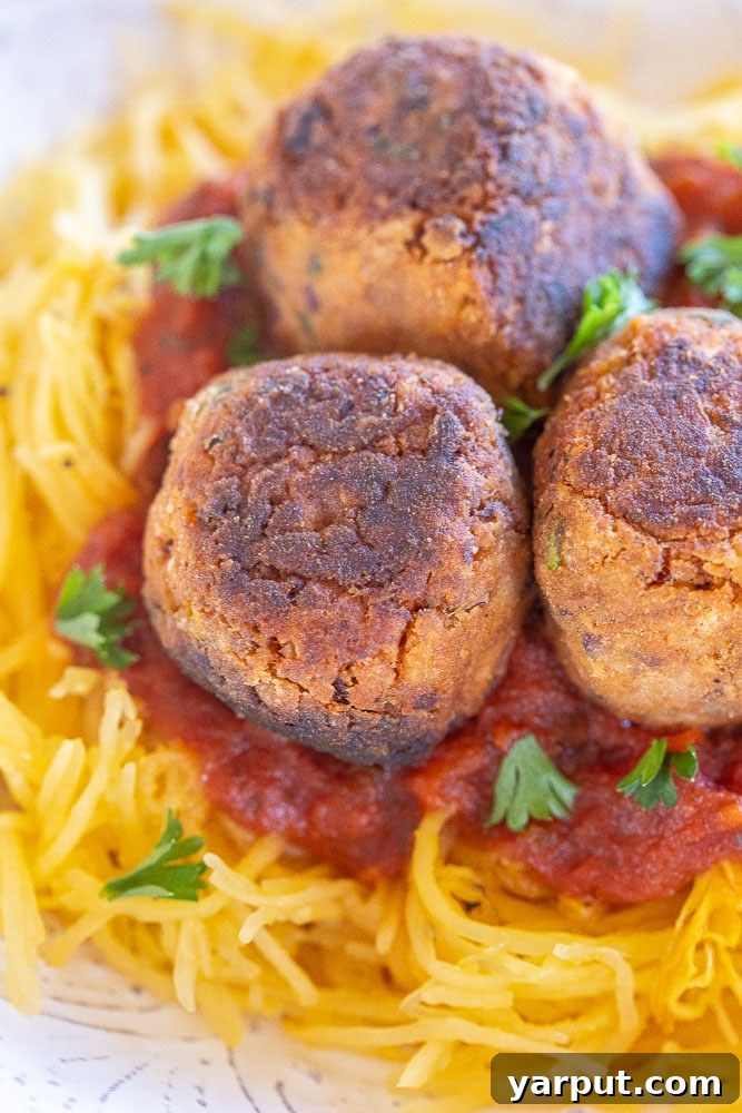 Close up of perfectly cooked veggie meatballs on top of spaghetti squash, ready to serve.