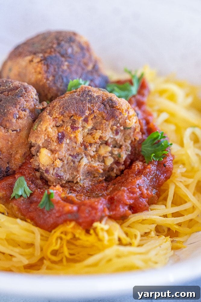 A vegan meatball with a bite taken out of it, showing its tender interior.