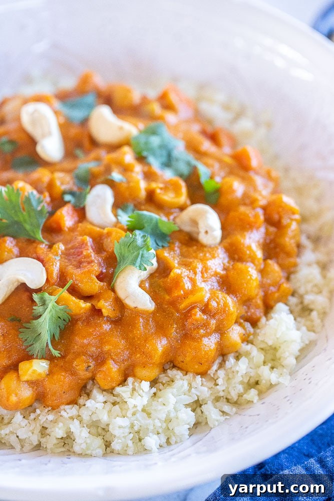 Creamy One-Pot Vegan Pumpkin Curry 4 Close up of a bowl of vegan pumpkin curry garnished with fresh cilantro and a swirl of coconut cream