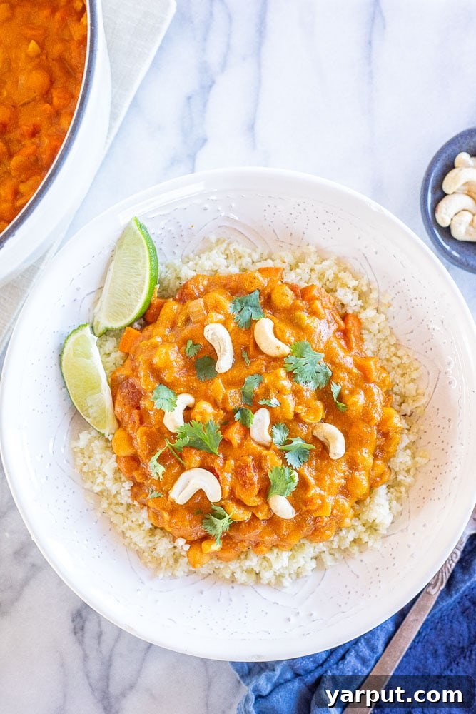 Creamy One-Pot Vegan Pumpkin Curry 6 Flatlay photo of a bowl of pumpkin curry served over cauliflower rice with lime wedges and cilantro