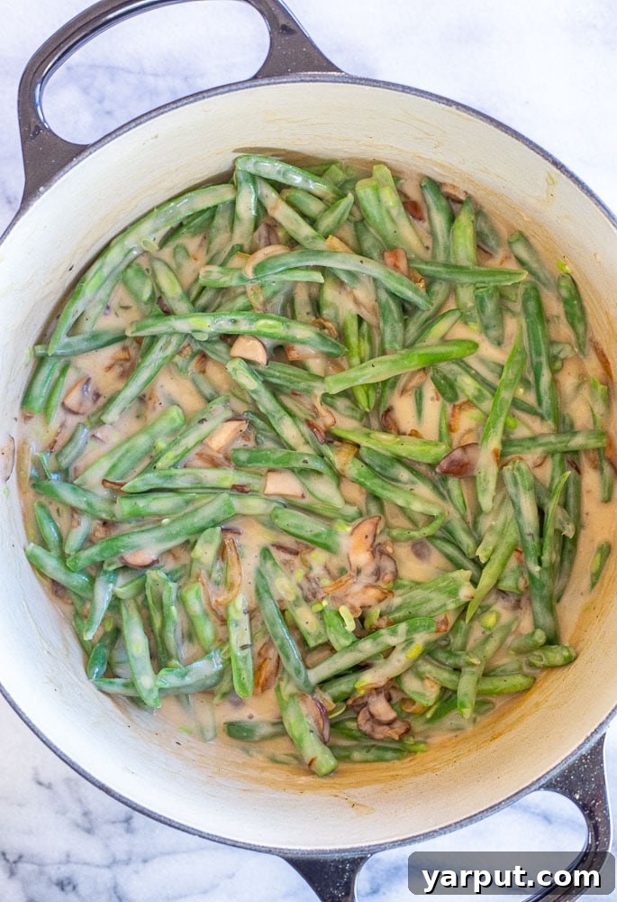 Ultimate Vegan Green Bean Casserole 4 A close-up shot of the raw vegan green bean casserole mixture in a baking dish, before baking, showing the creamy sauce and green beans evenly combined.