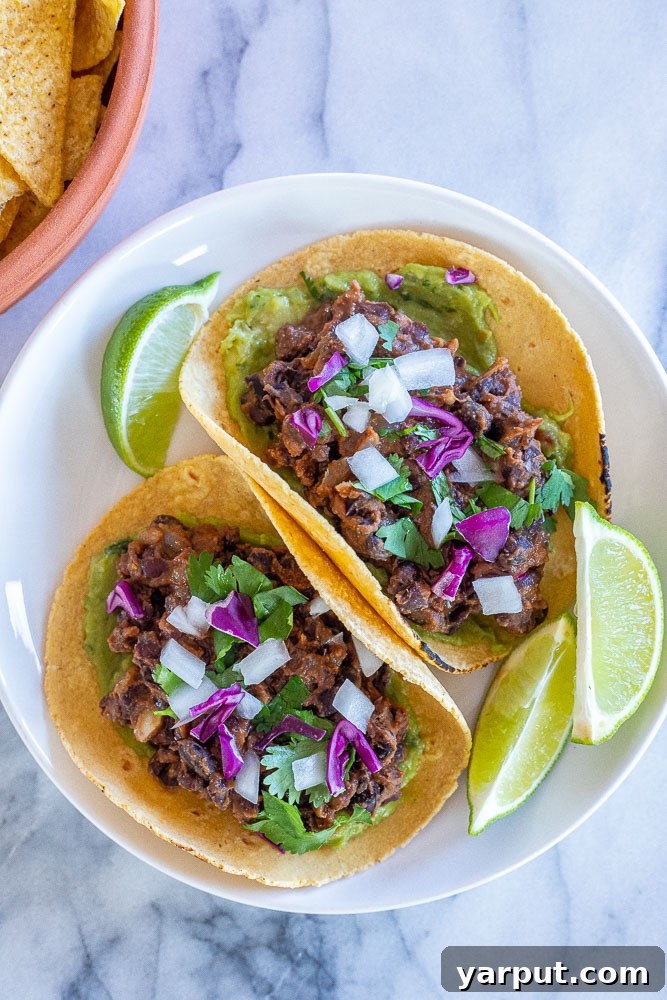 Effortless Vegan Black Bean Tacos 5 a plate of vegan black bean tacos, generously topped with fresh ingredients and served with tortilla chips