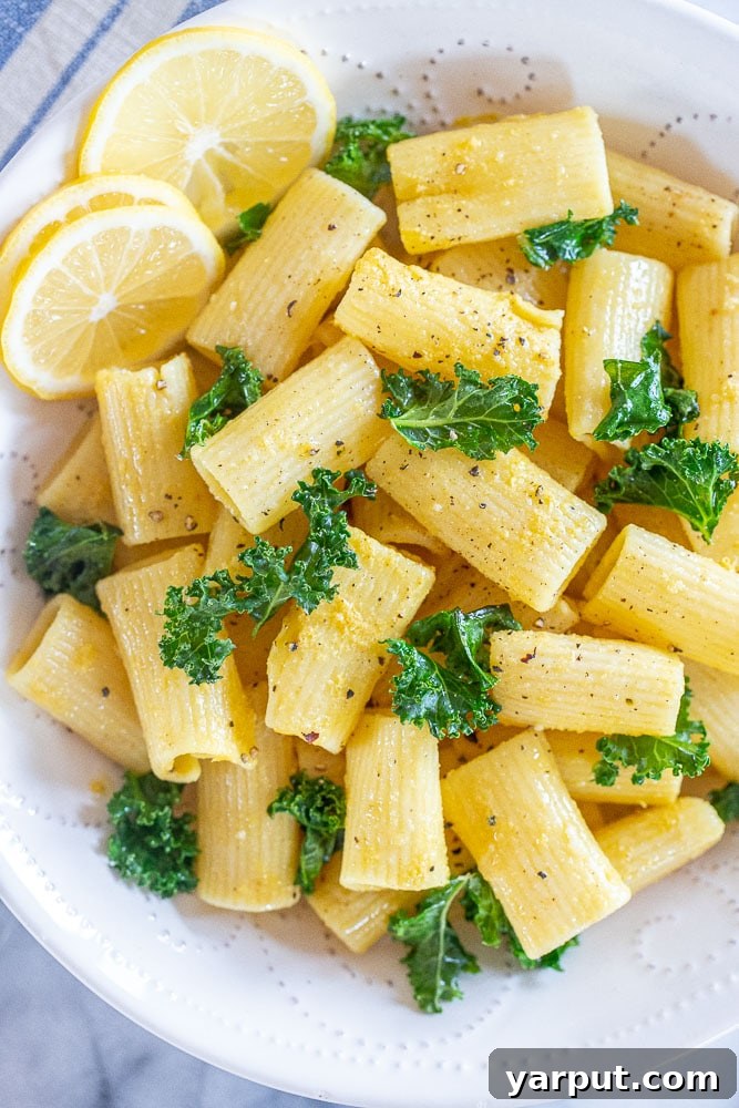 A vibrant, close-up image of Lemon Garlic Pasta, perfectly tossed with a creamy sauce and green leafy vegetables, highlighting its appealing texture and freshness.