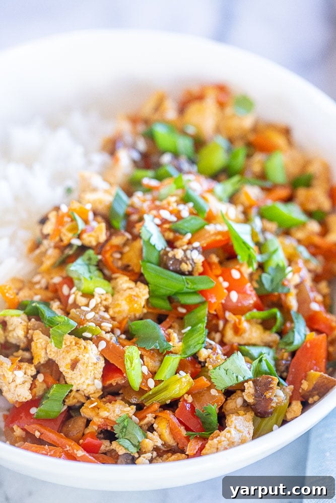 Korean Tofu & Veggie Power Bowls 5 A close-up shot of a vibrant Korean-inspired tofu bowl, showcasing crispy tofu, a medley of colorful vegetables, and rice, perfectly coated in sauce and garnished.