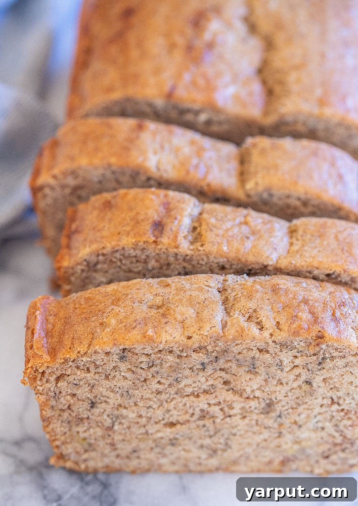 Decadent Vegan Banana Bread 6 Slices of freshly baked vegan banana bread stacked neatly on a cutting board, ready to be enjoyed.