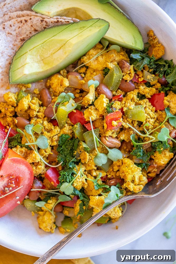 Plant-Powered Breakfast Bowls 5 Close-up of a vibrant vegan breakfast bowl, showcasing tofu scramble, fresh avocado, tomato, and hot sauce