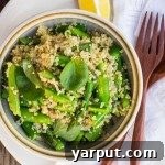 Close-up overhead view of the Spring Quinoa Salad in a serving bowl, with a corner of the bowl visible, showcasing the texture and colors of the ingredients.