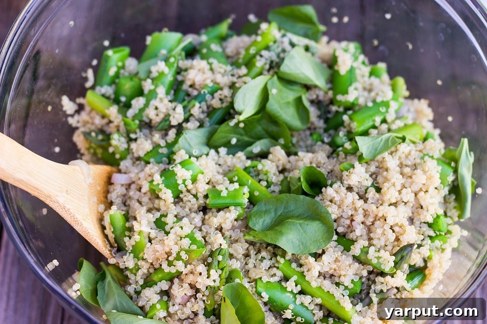 A close-up of a generously portioned Spring Quinoa Salad in a serving bowl, showcasing the vibrant mix of quinoa, green vegetables, and the light dressing.