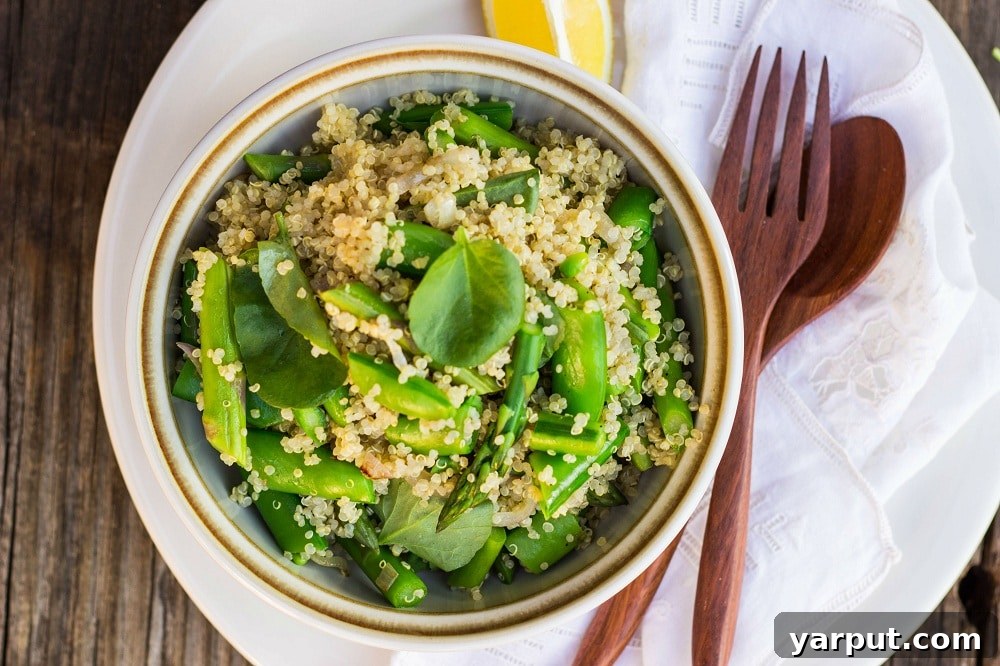 A large bowl of Spring Quinoa Salad, artfully arranged with a wooden fork, highlights the freshness and vibrant colors of the asparagus, sugar snap peas, watercress, and fluffy quinoa.