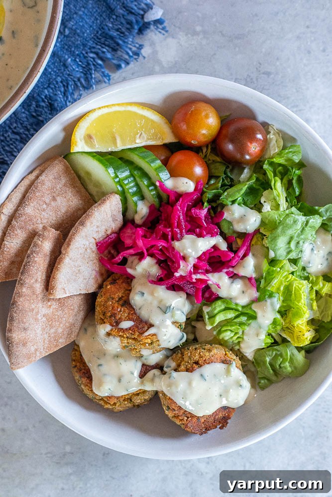 Creamy Vegan Tzatziki Dip 6 A stunning spread featuring vegan tzatziki sauce in a bowl, surrounded by warm pita bread, golden falafel, and a colorful assortment of fresh vegetables.