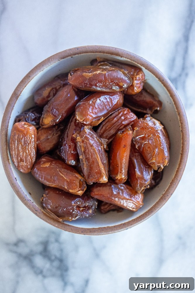 A beautiful display of plump, ripe Medjool dates, highlighting their natural sweetness and readiness for transformation into paste, arranged neatly in a bowl.