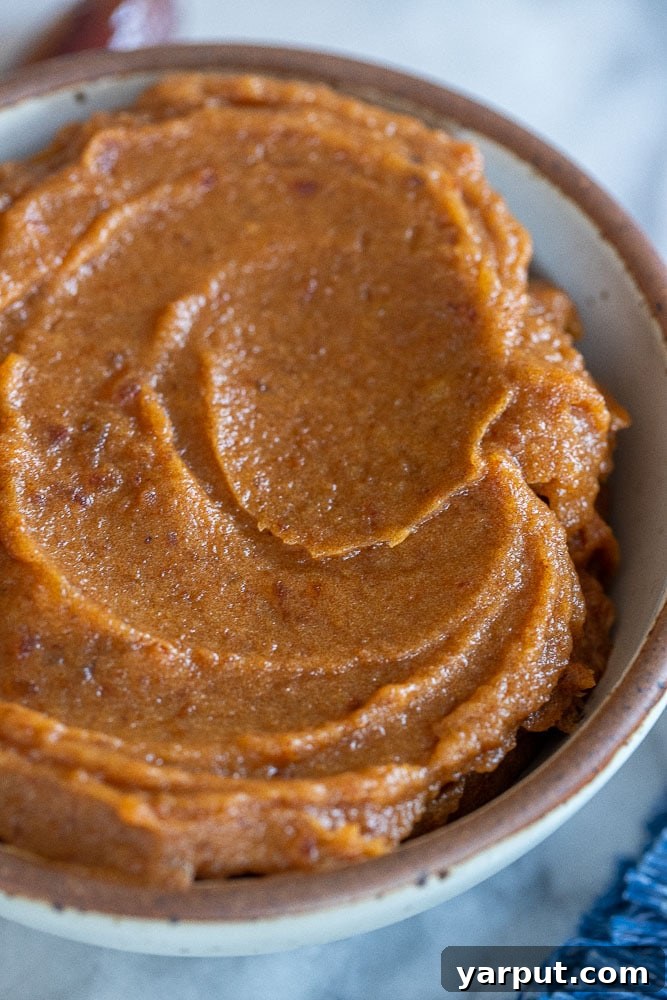 A close-up shot of creamy, smooth date paste in a bowl, showcasing its rich texture and natural appeal as a healthy sugar alternative, ready for various culinary uses.