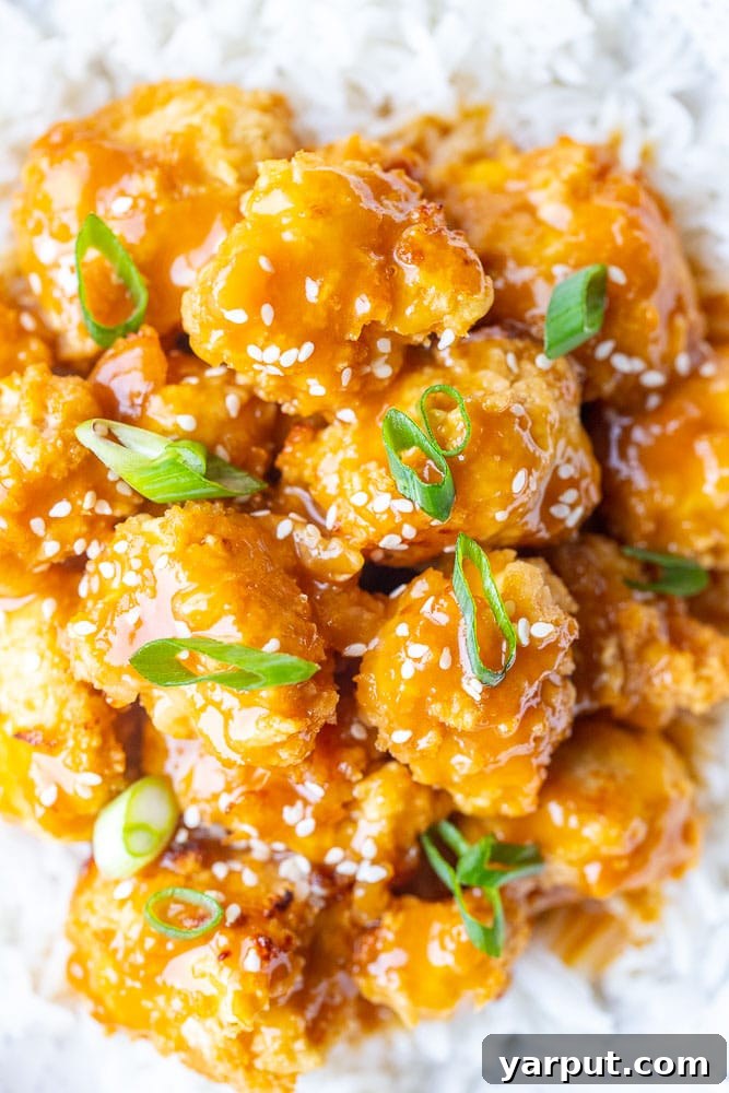 Crispy Zesty Vegan Orange Chicken 4 Close-up shot of individual crispy vegan orange chicken pieces, showcasing the glossy sauce, golden-brown crust, and flecks of sesame seeds, ready to be enjoyed.