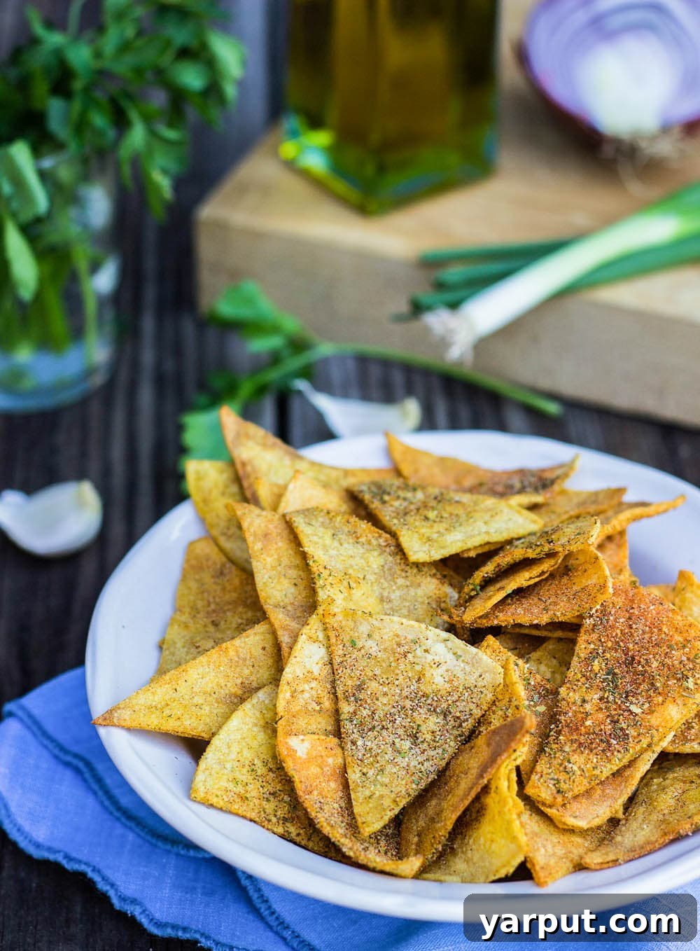 A vibrant bowl of Homemade Cool Ranch Doritos, generously seasoned with fresh herbs visible in the background, showcasing their irresistible crunch and flavor. Perfect for healthy snacking.