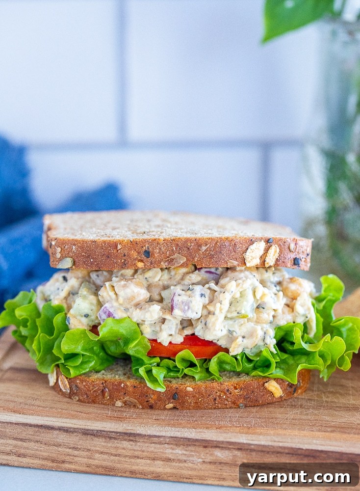 The Ultimate Plant-Based Tuna Salad 6 A vegan tuna salad sandwich on a cutting board, garnished with fresh lettuce and tomato, ready to be enjoyed.