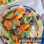 A vibrant close-up of a spicy potato taco with black beans, topped with fresh cilantro, capturing its delicious appeal.