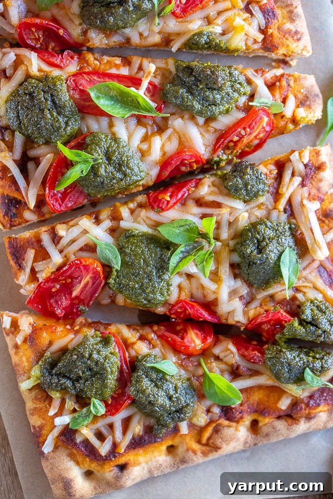 Trader Joe's Simple 5-Ingredient Vegan Tomato Pesto Pizza 5 Close-up shot of a slice of the delicious vegan pizza recipe, showing the melted cheese, pesto, and tomatoes