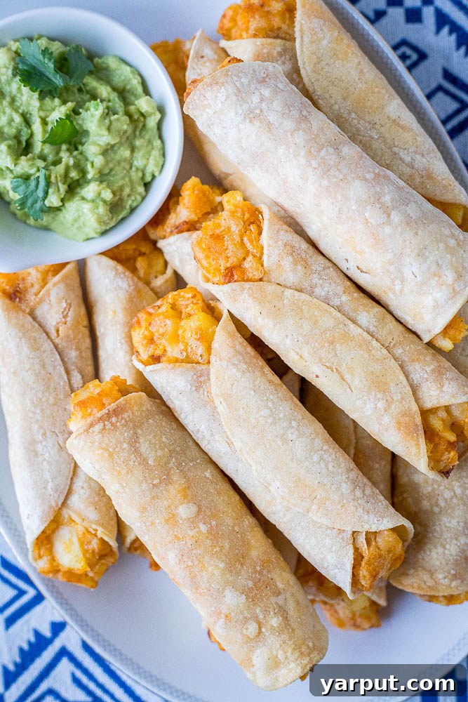 Crispy Cheesy Potato Taquitos filled with seasoned mashed potatoes and melted cheese, served with a side of salsa.